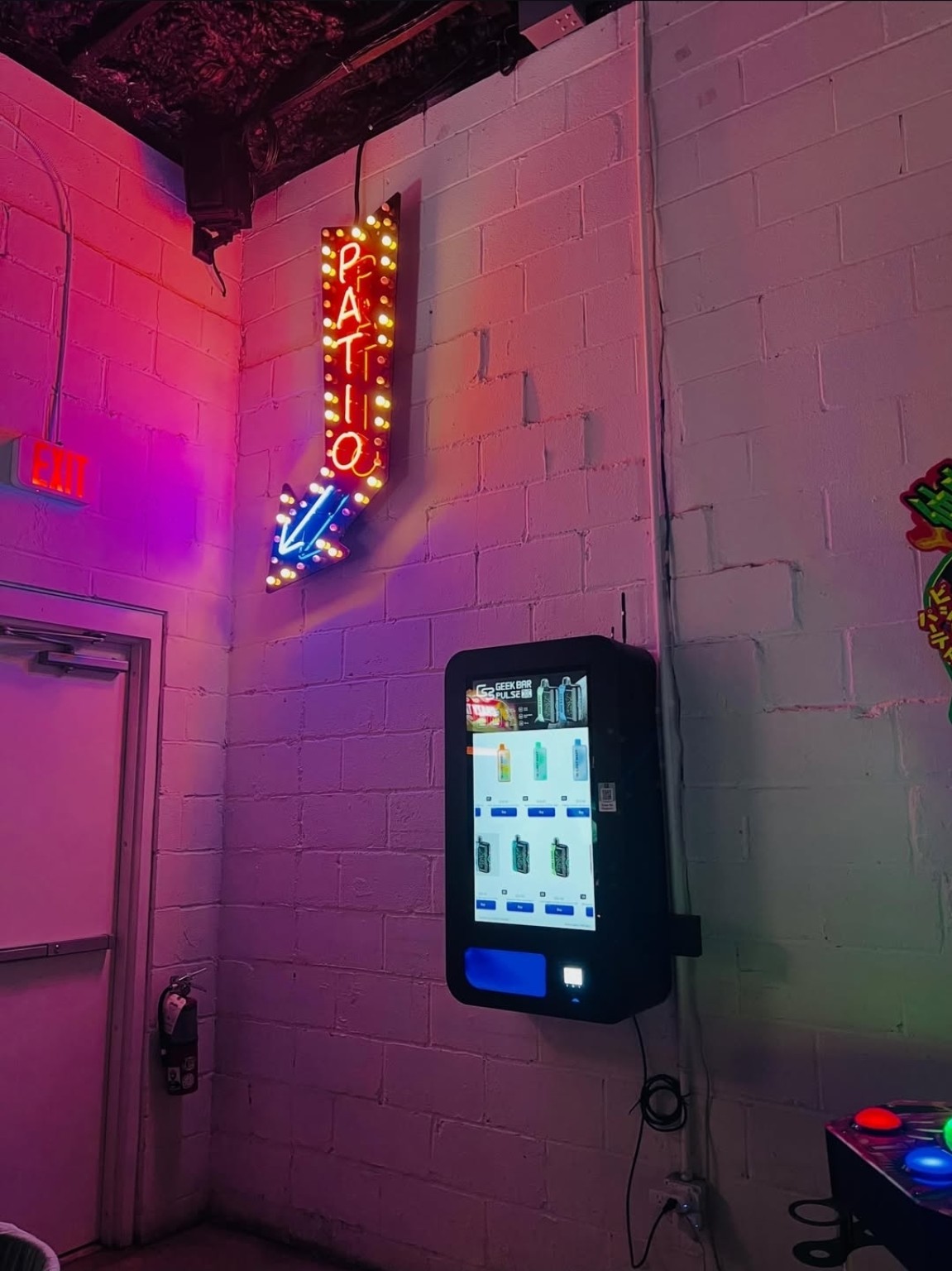 Vixen's wall-mounted vending machine beside the illuminated patio sign at Abari.