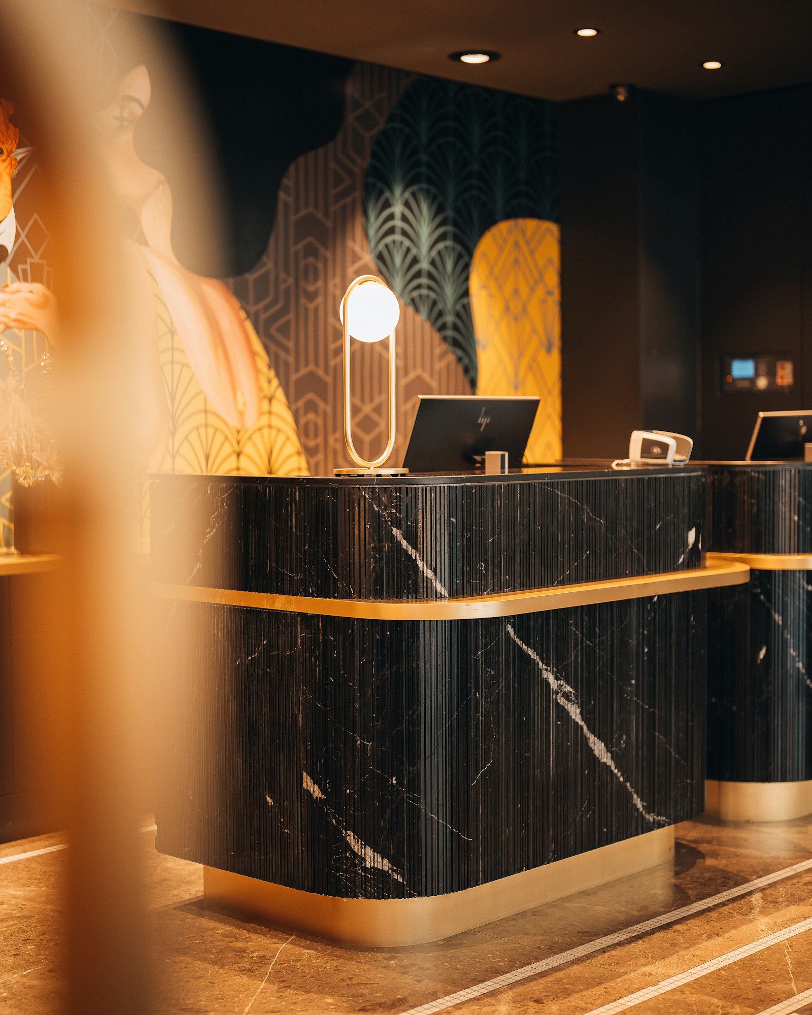 Hotel reception with a black marble desk and warm gold details, illustrating a hospitality setting.