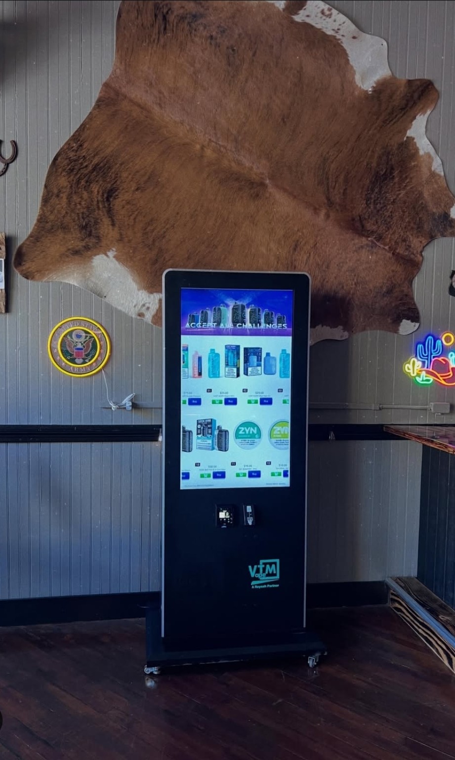 Vixen Vending's freestanding touchscreen machine at Over Yonder, beneath the venue's cowhide wall display.